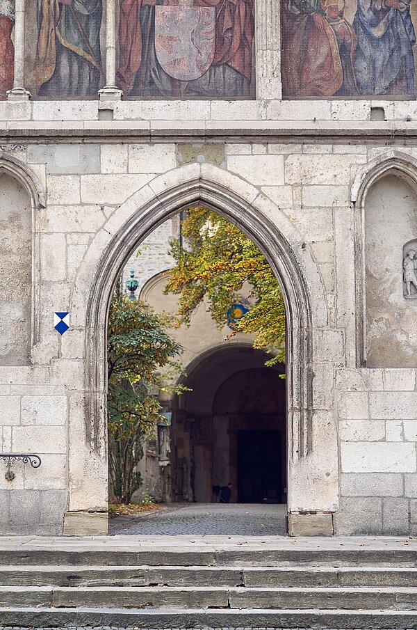 Blick auf einen steinernen Rundbogen, der in eine Kirche führt.